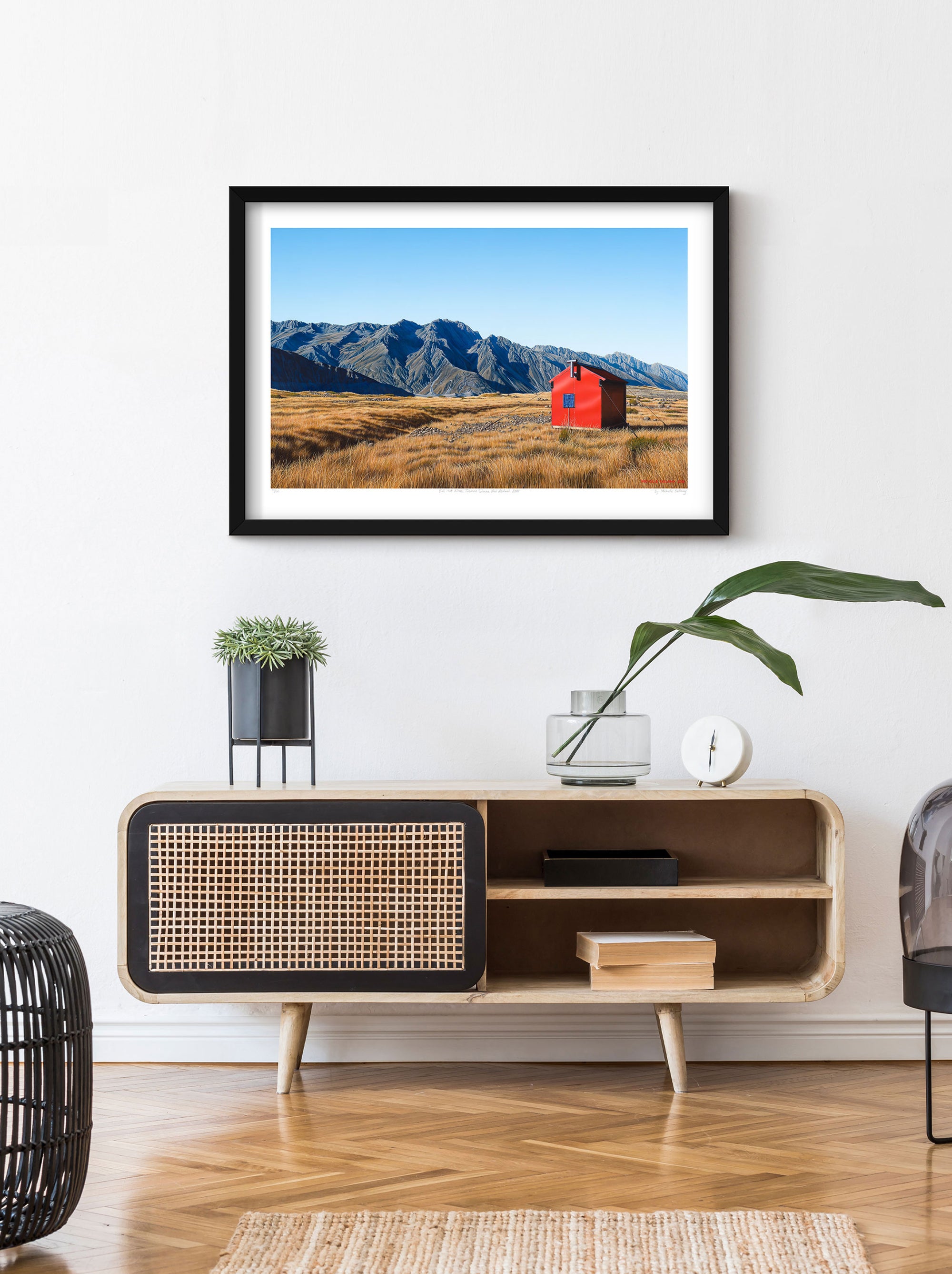 Limited edition art reproduction of 'Ball Hut Alone' above a side table in a hallway by Michelle Bellamy, featuring a rugged landscape of Aoraki/Mount Cook National Park with views towards the Tasman Glacier