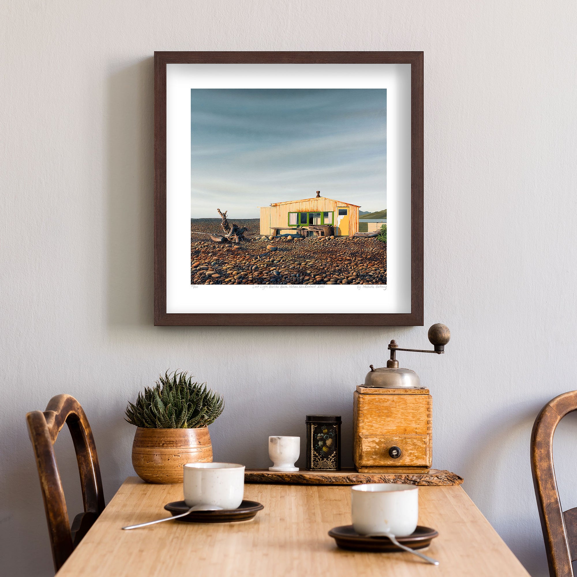 Limited edition art reproduction 'Last Light at the Boulder Bank', Nelson, New Zealand by Nelson artist Michelle Bellamy. Above dining room table and framed in a dark brown frame.
